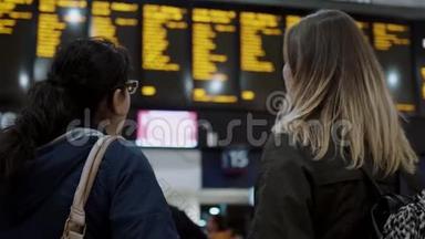 两名年轻女子在火车站检查发车时间